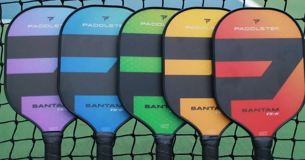 Dàn vợt Bantam nhiều màu của Paddletek treo trên lưới sân pickleball