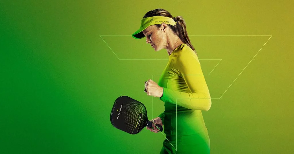 Nữ vận động viên Paddletek đội mũ lưỡi trai cầm vợt Tempest trên nền xanh lá